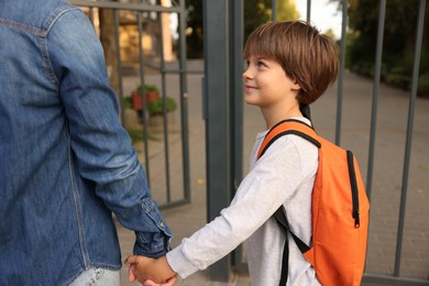 Photo of Mother taking her son to school outdoors, closeup
