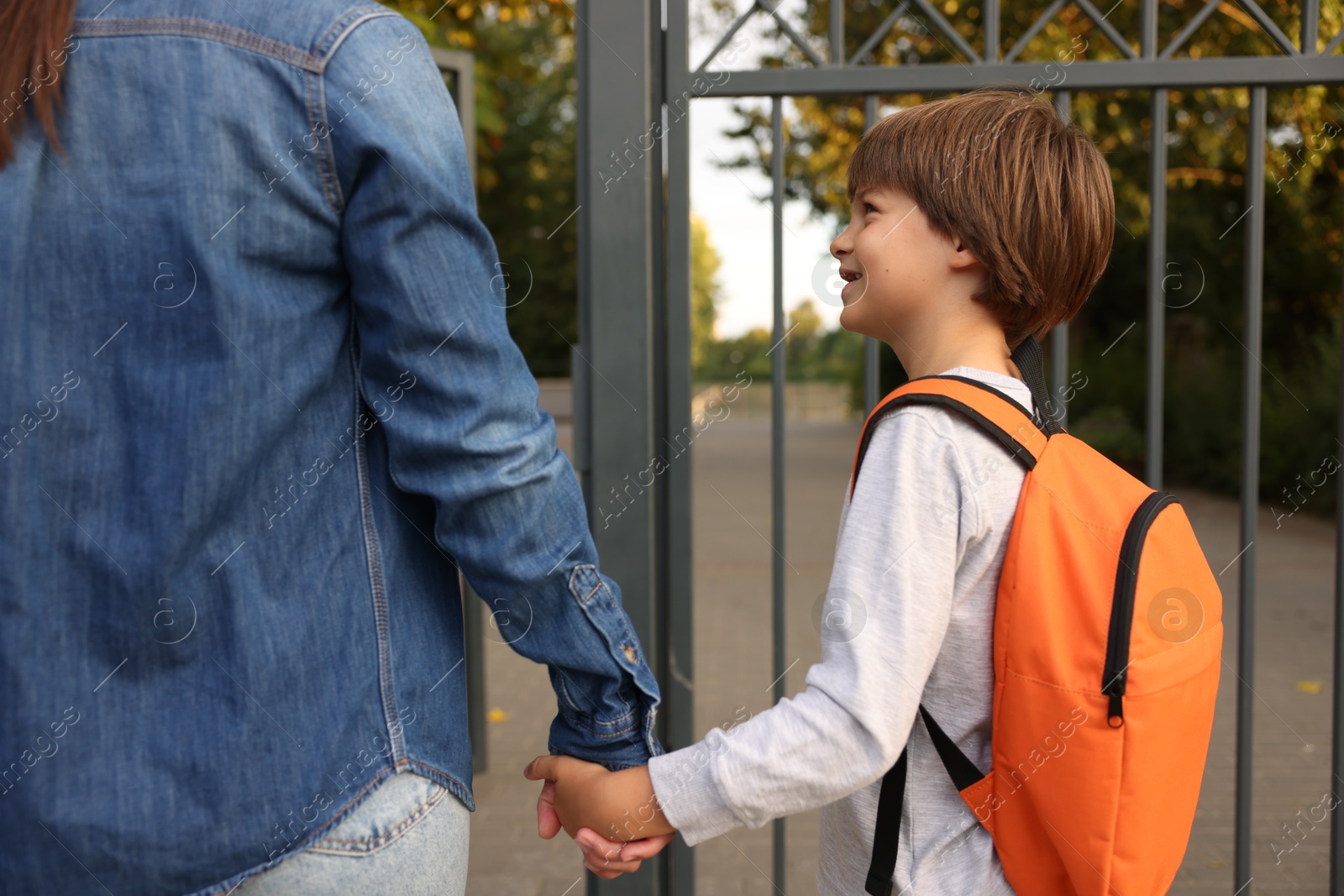 Mother taking her son to school outdoors, closeup Photo of Mother taking her son to school outdoors, closeup