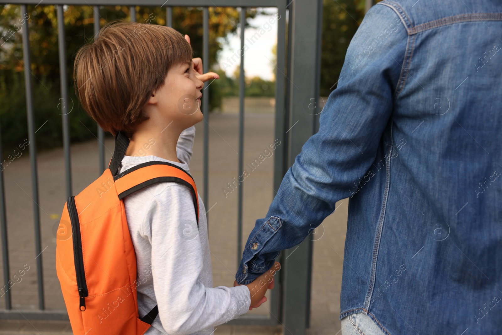 Mother taking her son to school outdoors, closeup Photo of Mother taking her son to school outdoors, closeup