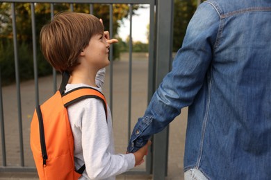 Photo of Mother taking her son to school outdoors, closeup