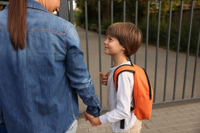 Photo of Mother taking her son to school outdoors, closeup