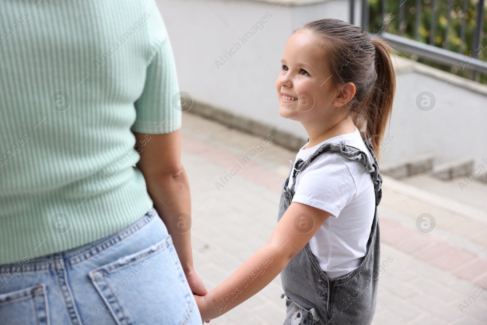 Mother taking her daughter to school outdoors, closeup Photo of Mother taking her daughter to school outdoors, closeup