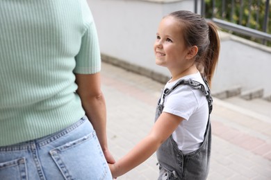 Photo of Mother taking her daughter to school outdoors, closeup