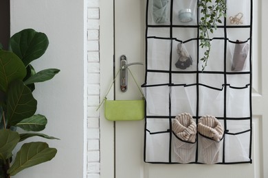 Photo of Organizer with different stuff on door and houseplant indoors