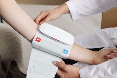 Photo of Doctor checking woman's heart rate and blood pressure via sphygmomanometer indoors, closeup