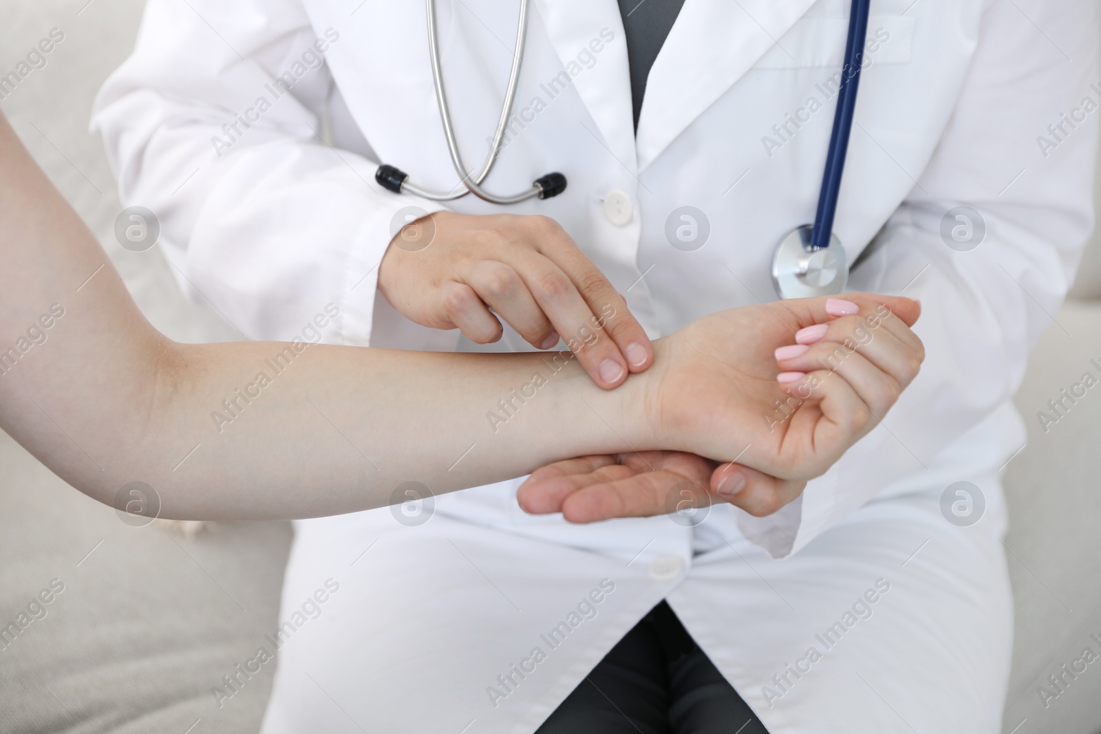 Doctor checking woman's pulse with fingers indoors, closeup Photo of Doctor checking woman's pulse with fingers indoors, closeup