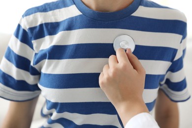 Photo of Doctor checking woman's heartbeat with stethoscope indoors, closeup