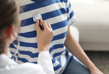 Photo of Doctor checking woman's heartbeat with stethoscope indoors, closeup