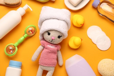 Photo of Baby bath accessories, care products and toys on orange background, flat lay