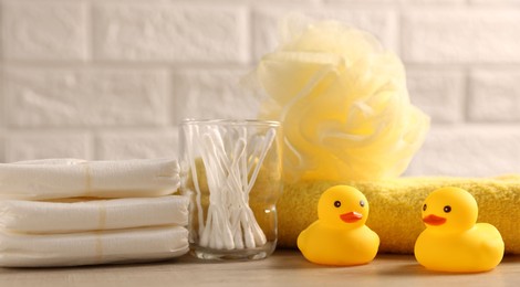 Photo of Baby bath accessories on wooden table against white brick wall, closeup
