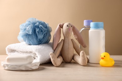Photo of Baby bath accessories, care products and toy on table against beige background