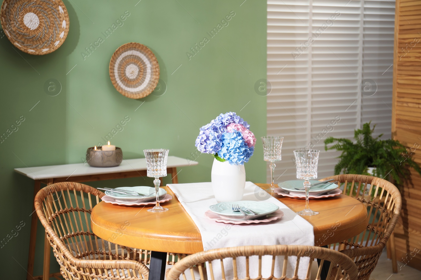 Photo of Stylish setting with plates and vase of flowers on wooden table in dining room. Interior design