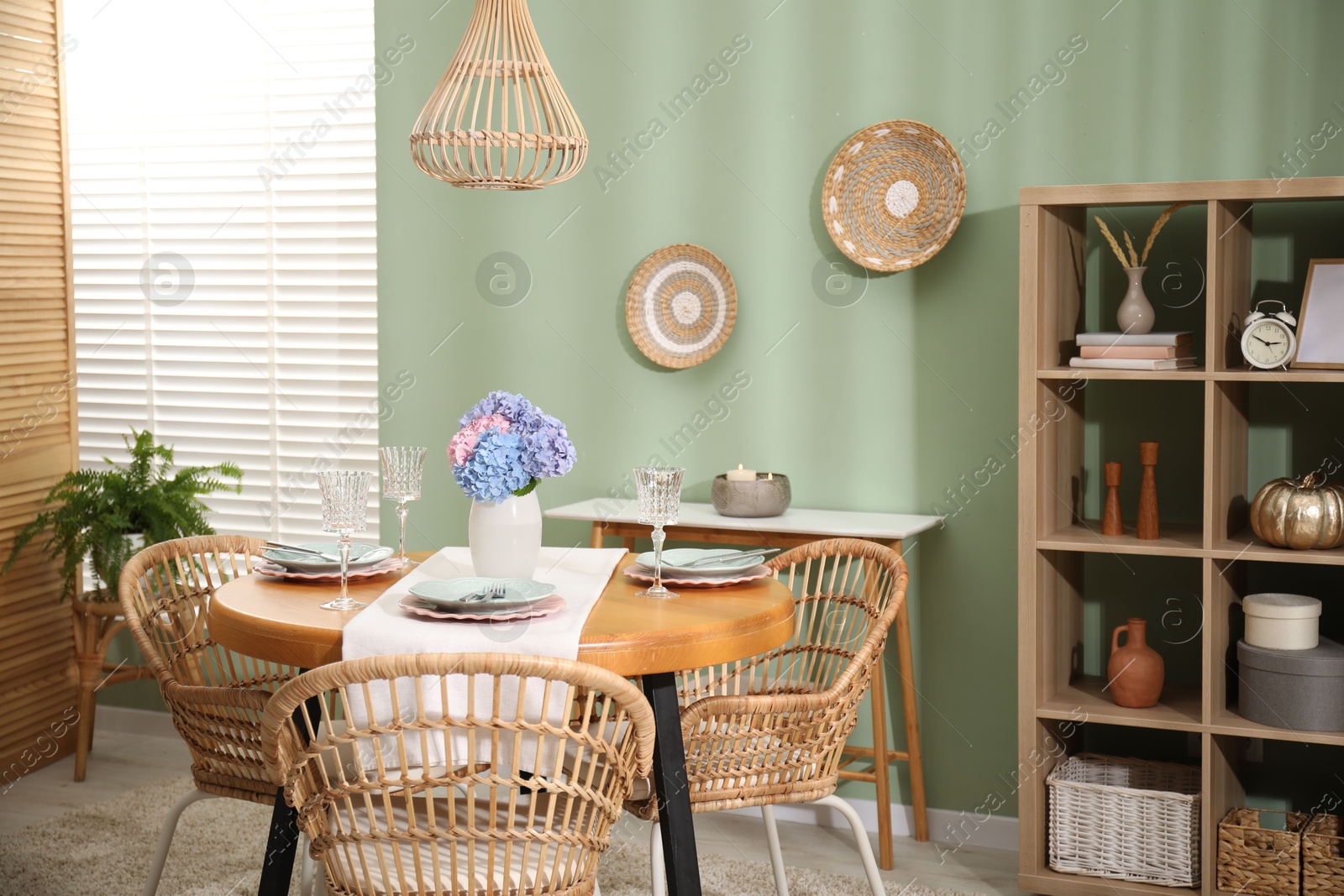 Photo of Stylish setting with plates and vase of flowers on wooden table in dining room. Interior design