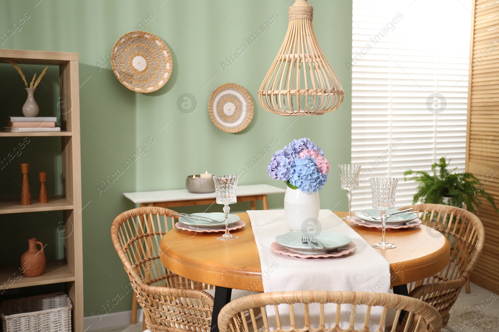 Photo of Stylish setting with plates and vase of flowers on wooden table in dining room. Interior design