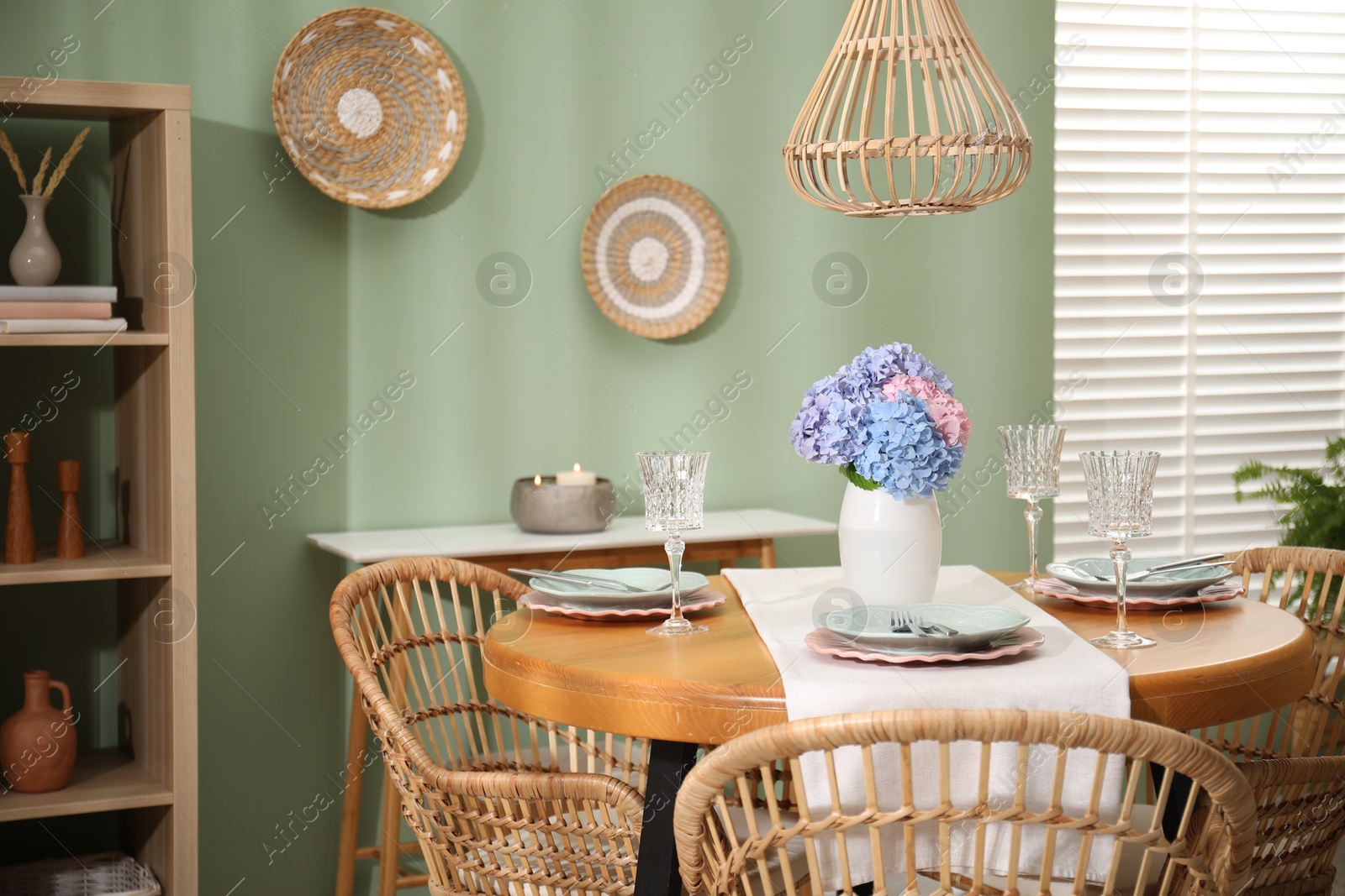 Photo of Stylish setting with plates and vase of flowers on wooden table in dining room. Interior design