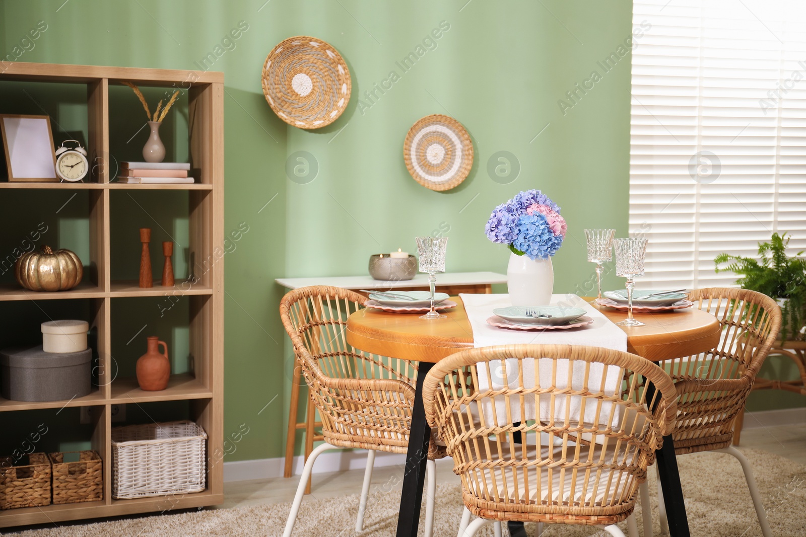 Photo of Stylish setting with plates and vase of flowers on wooden table in dining room. Interior design