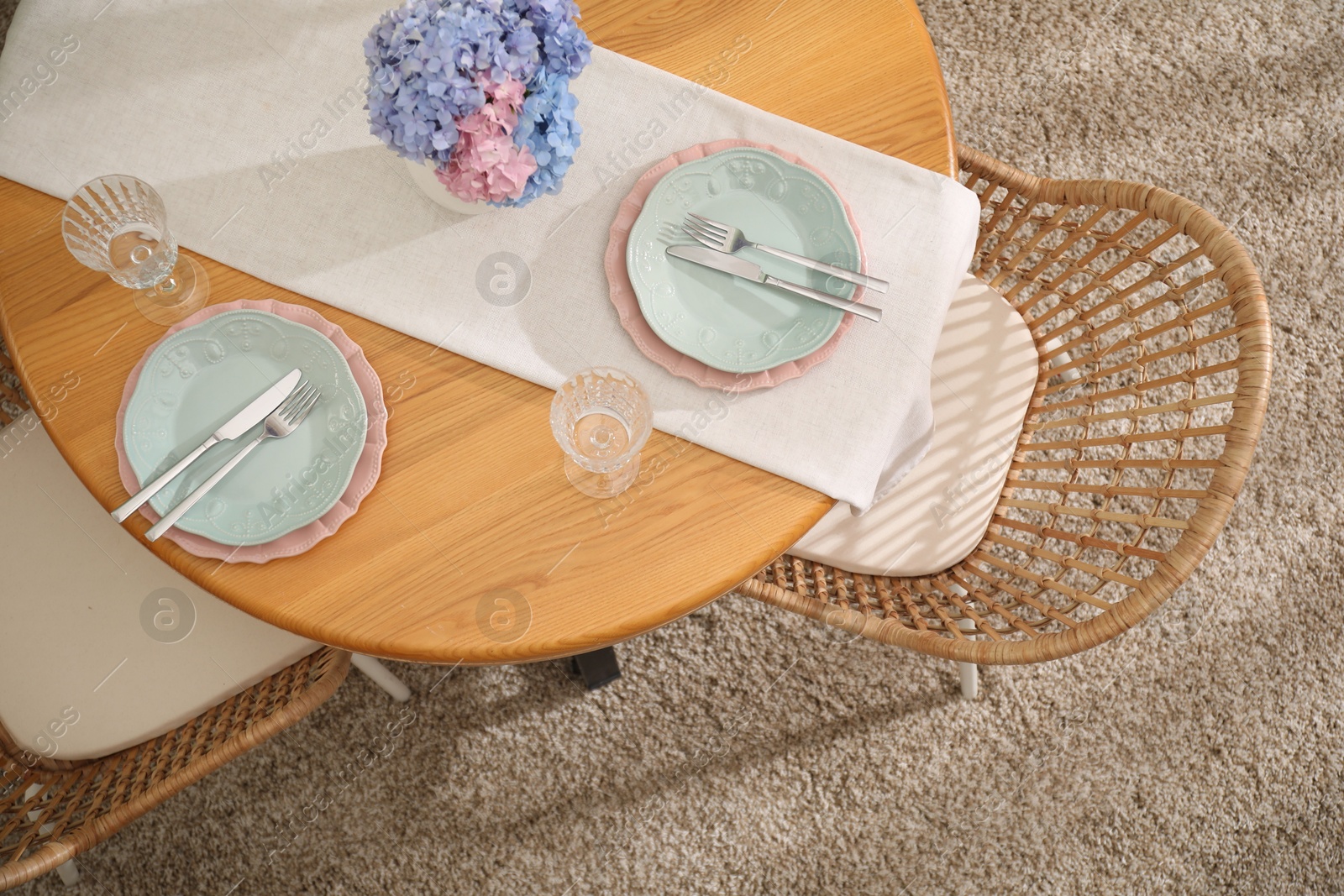 Photo of Stylish setting with plates and vase of flowers on wooden table in dining room, above view. Interior design