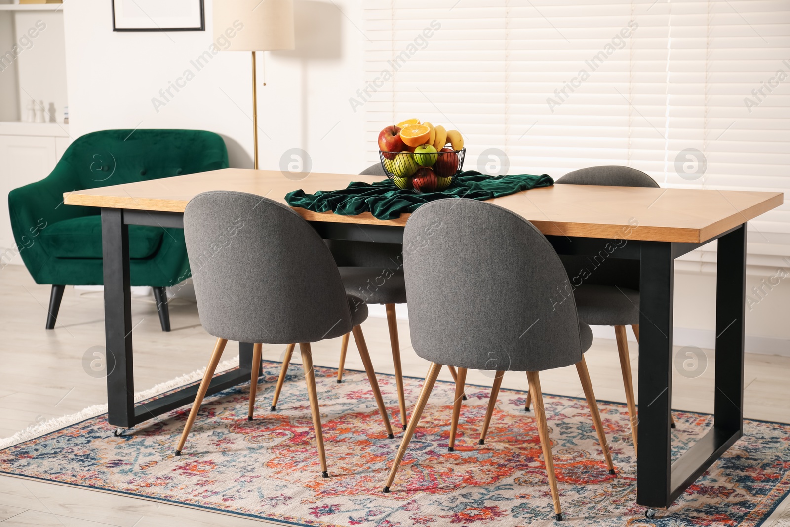 Photo of Bowl of fruits on wooden table in dining room. Interior design