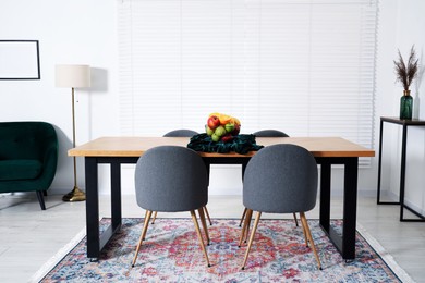 Photo of Bowl of fruits on wooden table in dining room. Interior design