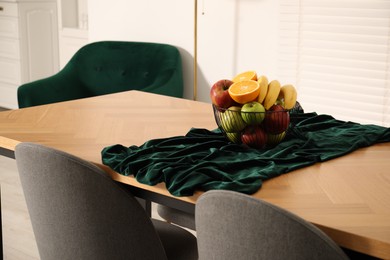 Photo of Bowl of fruits on wooden table in dining room. Interior design