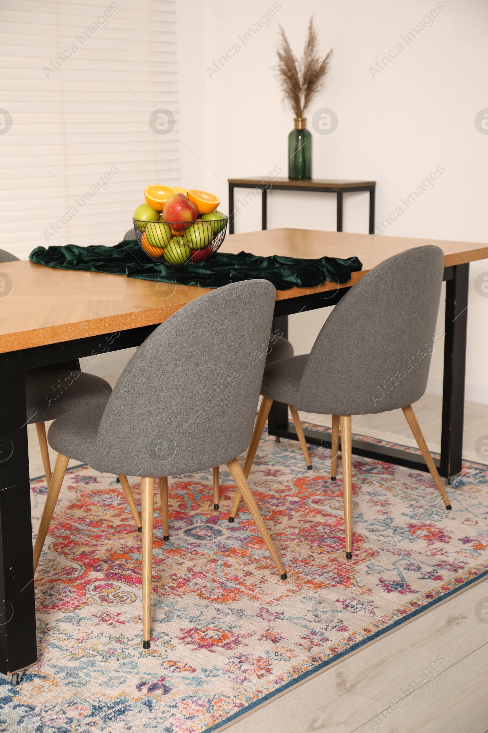 Photo of Bowl of fruits on wooden table in dining room. Interior design