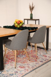 Photo of Bowl of fruits on wooden table in dining room. Interior design