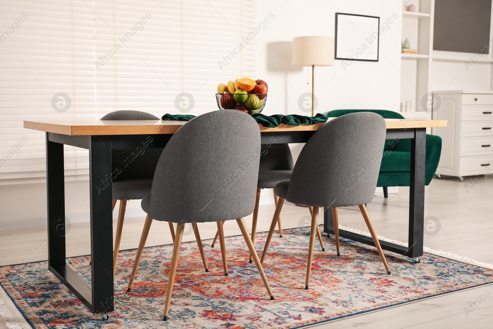 Photo of Bowl of fruits on wooden table in dining room. Interior design