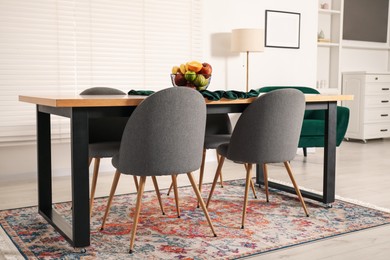 Photo of Bowl of fruits on wooden table in dining room. Interior design