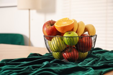 Photo of Bowl of fruits on wooden table in dining room. Space for text