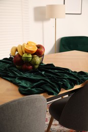 Photo of Bowl of fruits on wooden table in dining room. Interior design