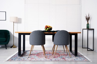Photo of Bowl of fruits on wooden table in dining room. Interior design