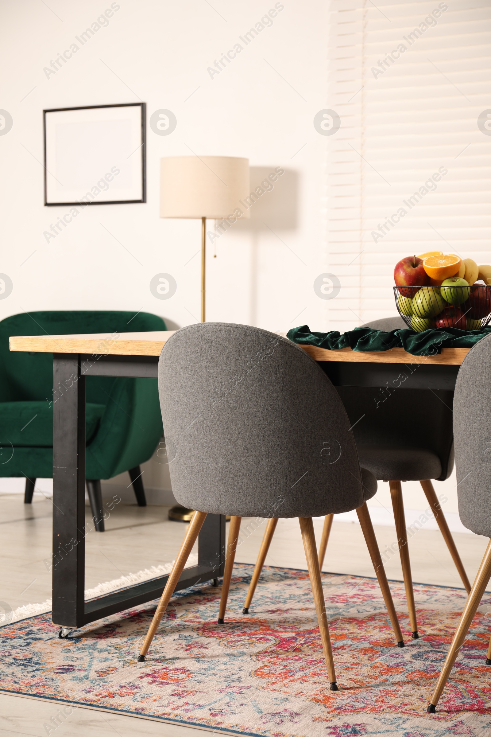 Photo of Bowl of fruits on wooden table in dining room. Interior design