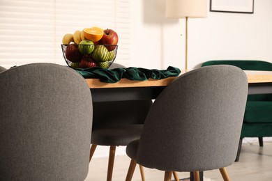 Photo of Bowl of fruits on wooden table in dining room. Interior design