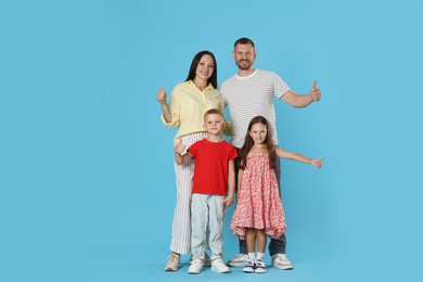Photo of Happy family showing thumbs ups on light blue background