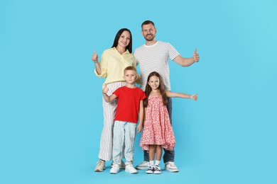 Photo of Happy family showing thumbs ups on light blue background
