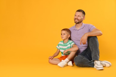 Photo of Happy father and son on yellow background. Space for text