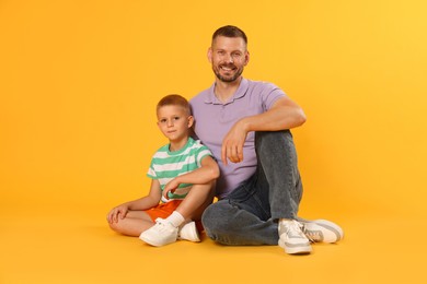 Photo of Happy father and son on yellow background
