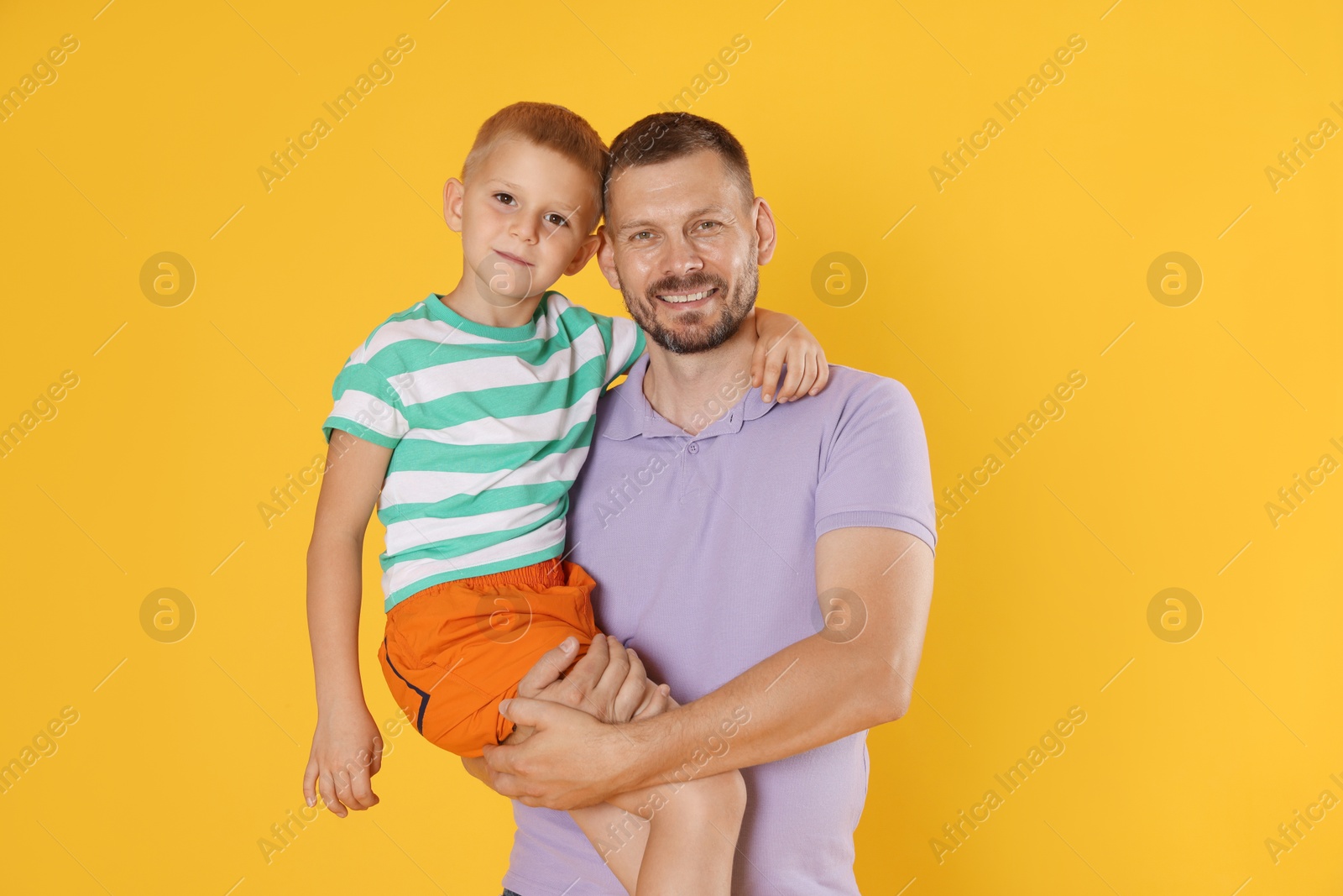 Happy father and son on yellow background Photo of Happy father and son on yellow background
