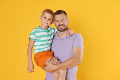 Photo of Happy father and son on yellow background