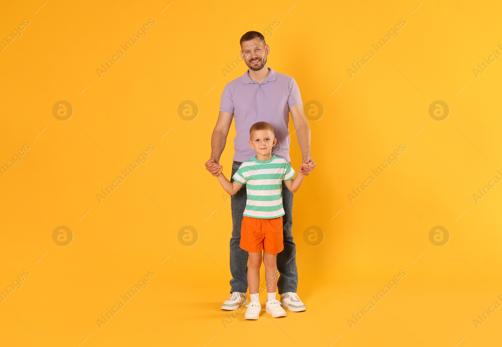 Photo of Happy father and son on yellow background