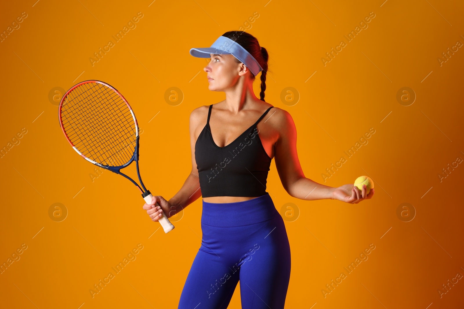 Photo of Woman with racket and tennis ball on orange background