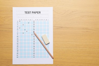 Photo of Student passing exam. Answer sheet, eraser and pencil on wooden table, flat lay. Space for text