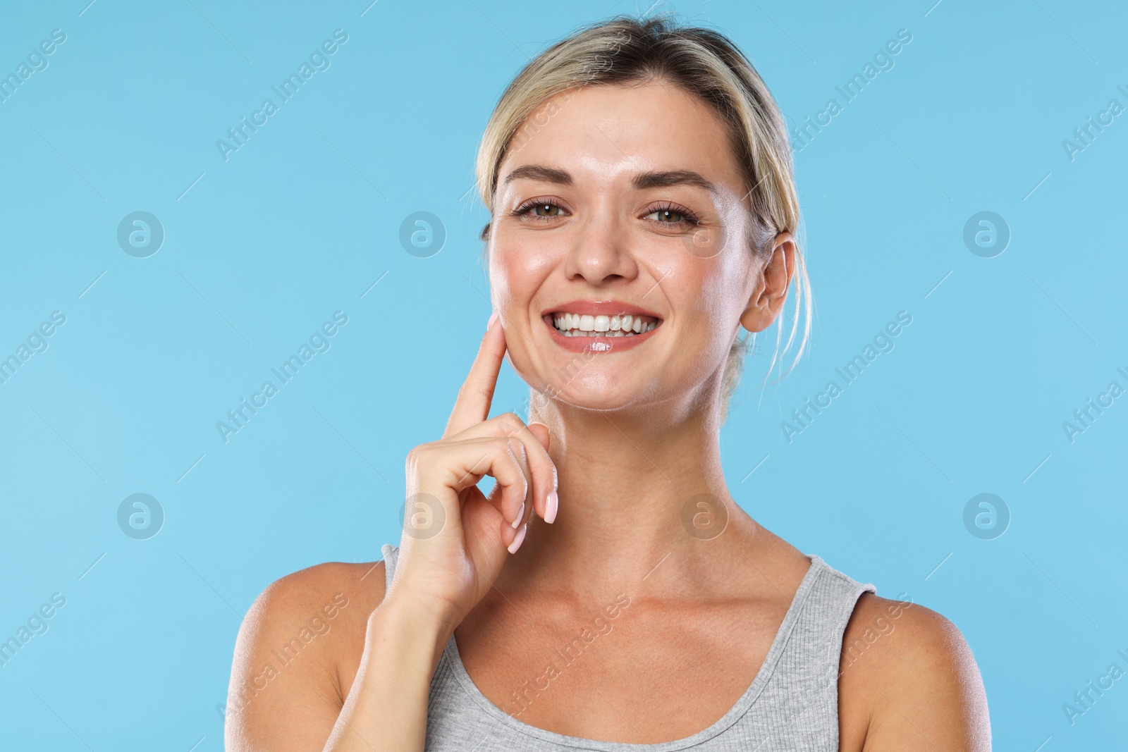 Photo of Woman with beautiful healthy teeth on light blue background