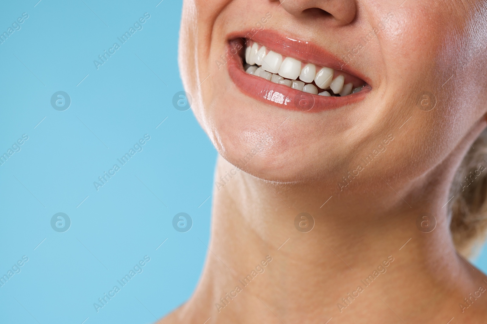 Photo of Woman with beautiful healthy teeth on light blue background, closeup. Space for text