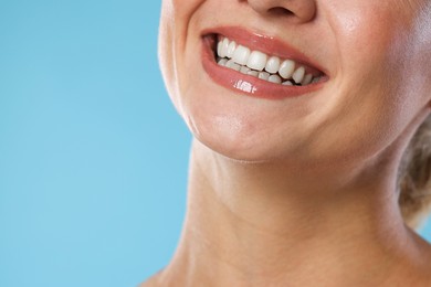 Photo of Woman with beautiful healthy teeth on light blue background, closeup. Space for text