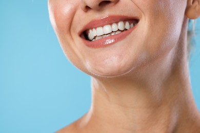 Photo of Woman with beautiful healthy teeth on light blue background, closeup