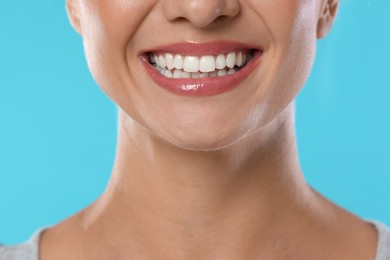 Photo of Woman with beautiful healthy teeth on light blue background, closeup