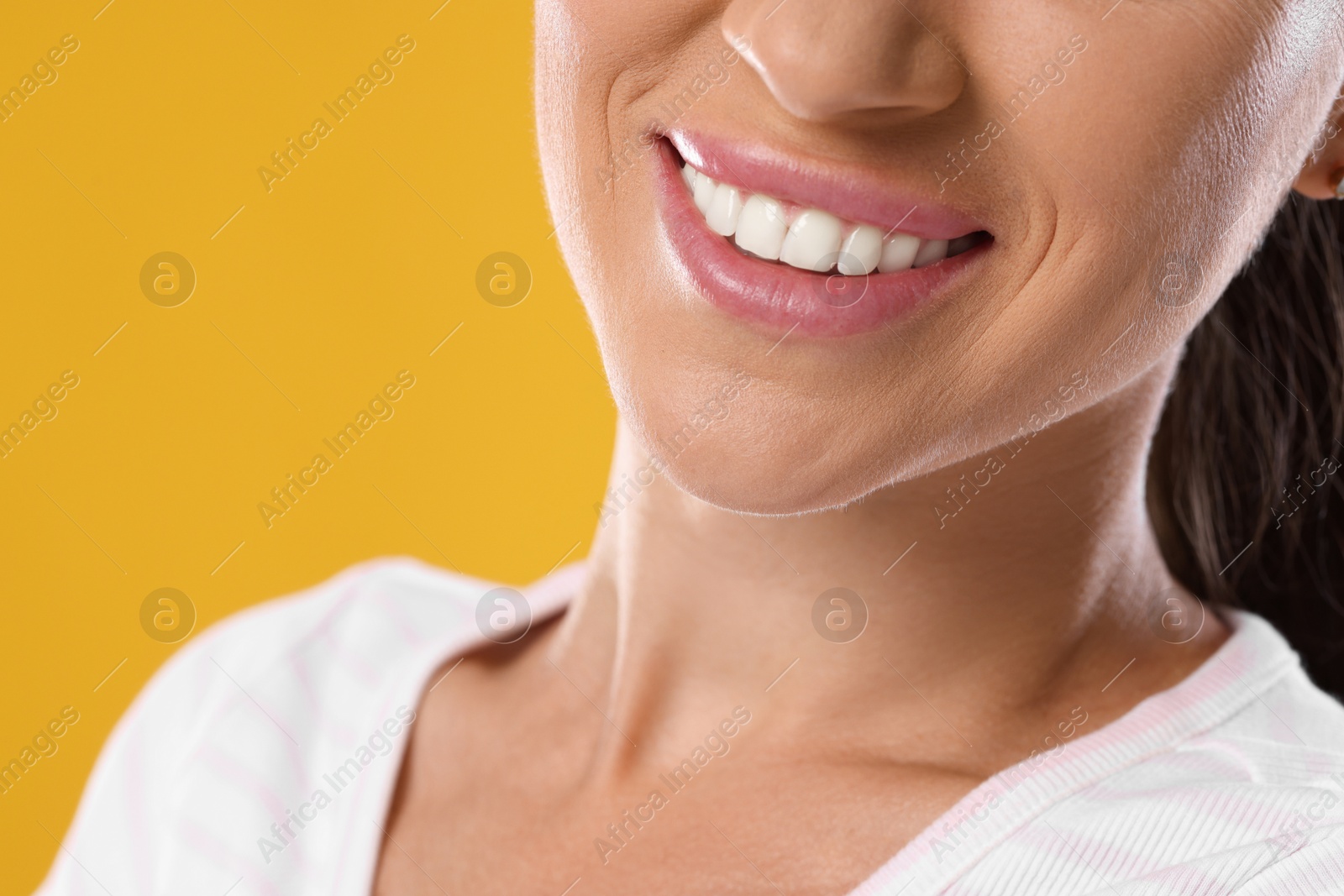 Photo of Woman with beautiful healthy teeth on yellow background, closeup