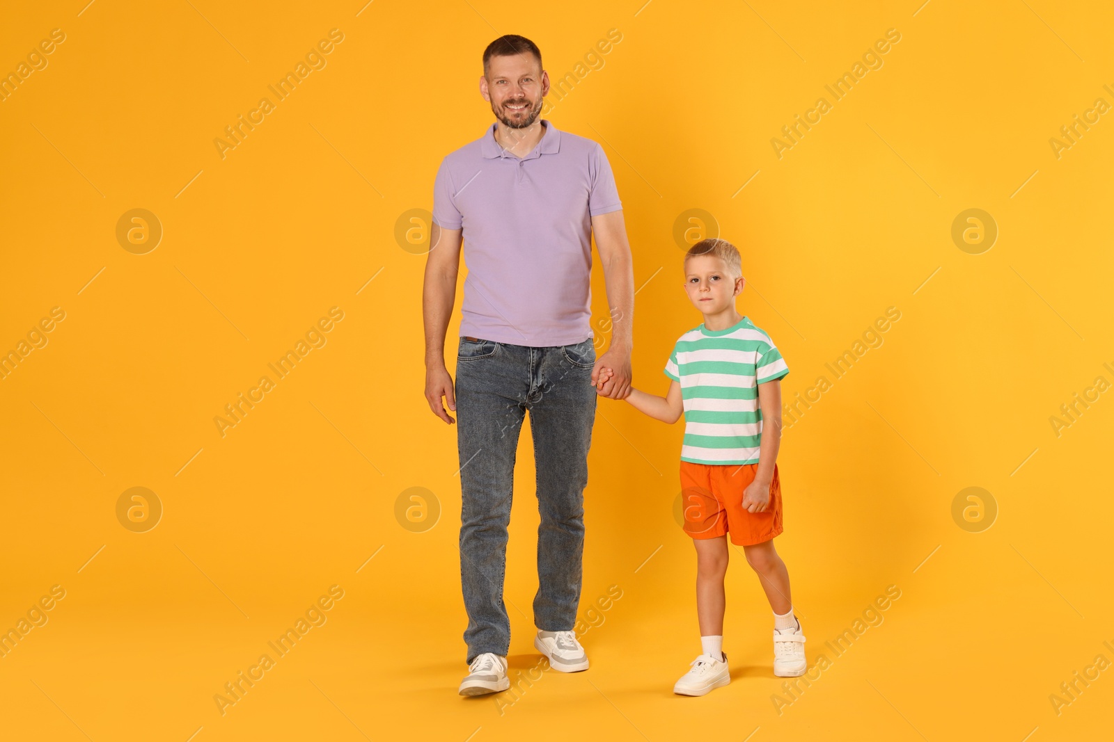 Happy father and son on yellow background Photo of Happy father and son on yellow background