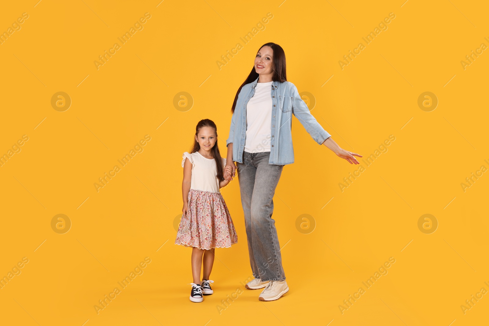Lovely mother and daughter on yellow background Photo of Lovely mother and daughter on yellow background